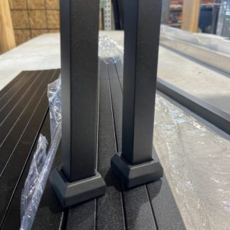 Two black aluminum balusters with base shoes on railing panel in warehouse