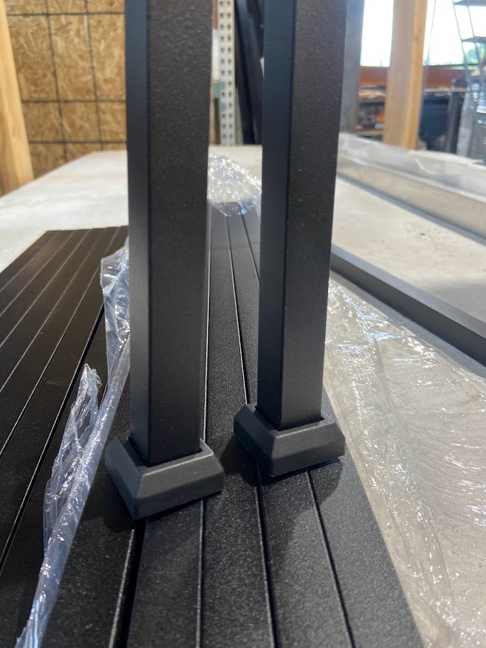Two black aluminum balusters with base shoes on railing panel in warehouse