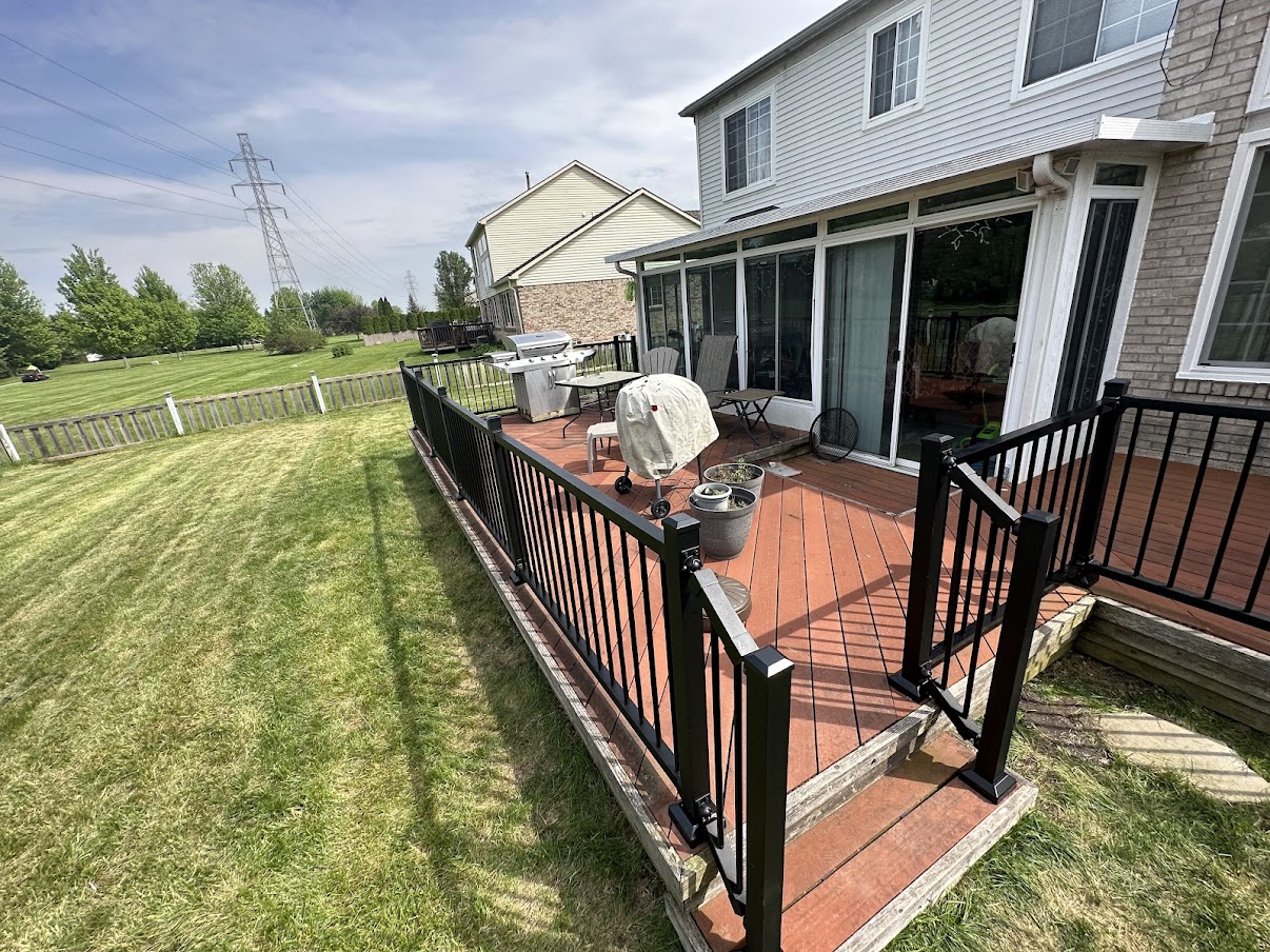 Residential backyard composite deck with full black aluminum railing system and gate section