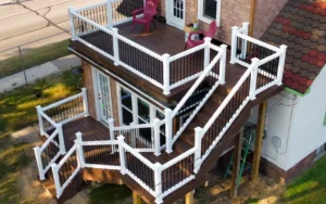 Aerial drone view of a multi-level elevated deck with white vinyl railing black aluminum balusters and stairway on a residential home