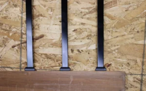 Black square aluminum balusters installed in a wood rail using baluster connectors on a workbench
